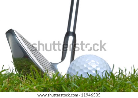 Close up of a golf ball lying in the grass with an iron club lined up for a shot. Studio shot, real grass.