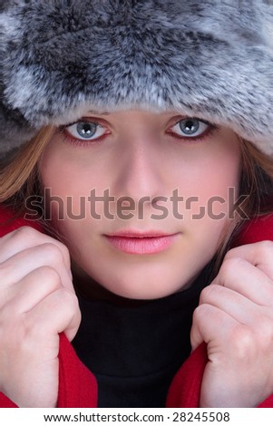 Close up of a woman wearing a fur hat and red coat with the collars pulled up.