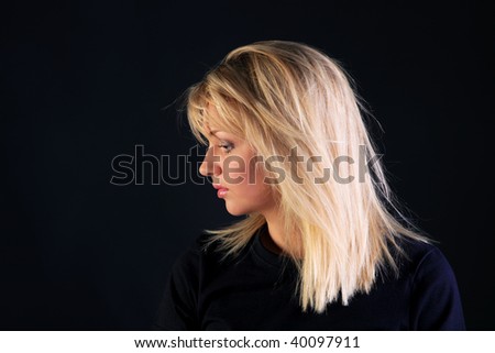 Portrait of a beautiful blonde haired woman with blue eyes on a black background side view.