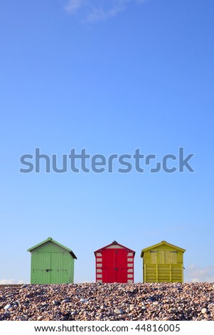 Three colourful beach huts against a bright blue sky, framed to allow copy space in the upper part of the image.