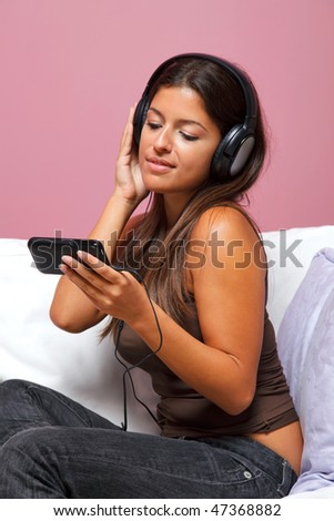 Woman sat in an armchair wearing headphones listening to a music video on her mp3 player