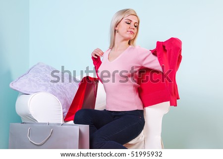 An attractive blond woman sat in a chair trying on some new clothes she\'s just bought.