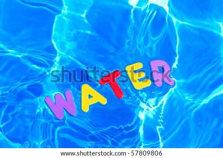 The word WATER made from foam letters floating on the water surface of a swimming pool