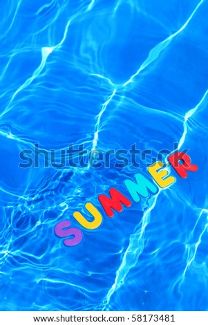 The word SUMMER made from foam letters floating on the water surface of a swimming pool