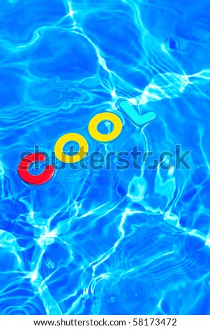 The word COOL made from foam letters floating on the water surface of a swimming pool