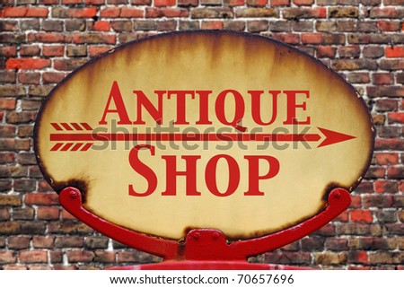 A rusty old retro arrow sign with the text Antique shop
