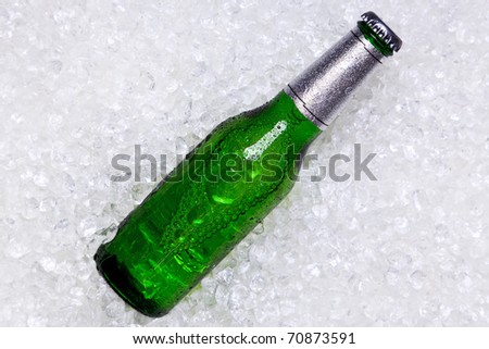 Photo of a green glass bottle of beer on crushed ice.