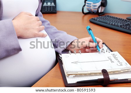 Photo of a pregnant woman in an office writing the words Maternity Leave in her diary.