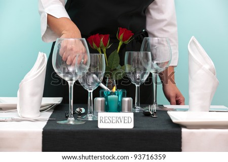 Photo of a waitress lighting a candle on a reserved table in a restaurant.