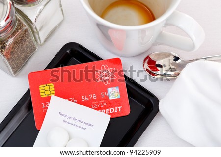 Photo of a credit card placed on a tray to pay for a restaurant bill. The card is a mock up designed and printed by myself, all the details including logos and hologram are generic.