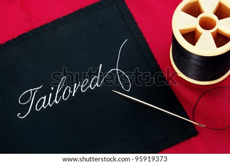 Photo of a garment label with the word Tailored on a red silk lining with a needle and reel of thread.