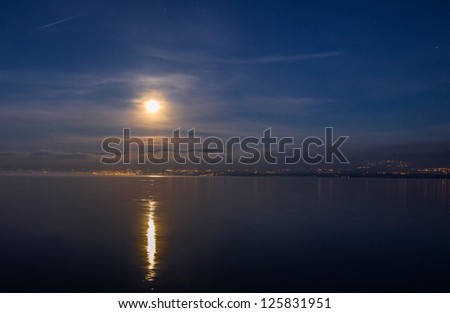 Full moon over Jura mountain range and Lake Geneva in a winter dawn