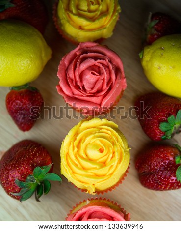 Cupcakes, lemon and strawberry on a pastry board.