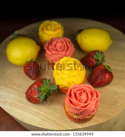 Cupcakes, lemon and strawberry on a pastry board.