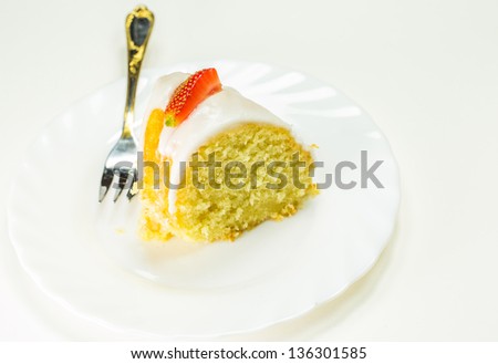 A slice of cheese pound cake coated with sugar glaze and pieces of strawberry