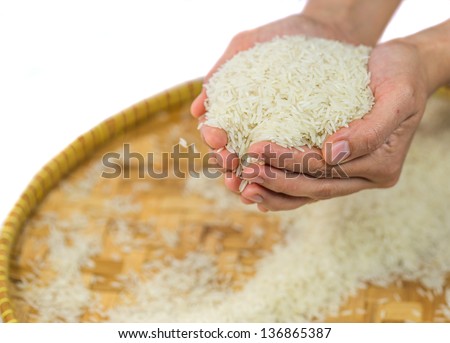 Hand releasing rice grain into a wicker tray