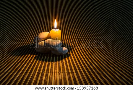 Zen stones and yellow candles on a bamboo mat