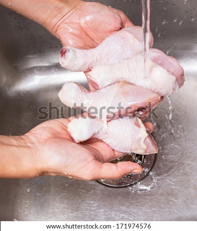 Female hands washing and cleaning chicken drumstick at the kitchen sink
