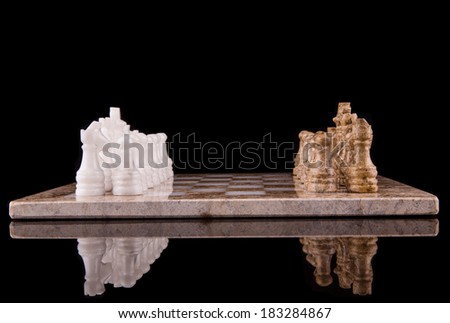 Stone made chess set over black background