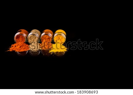 Mixed powdered spices in glass container over black background