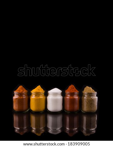 Mixed powdered spices in glass containers over black background