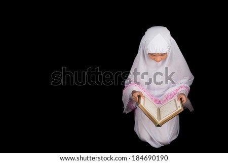Young Asian Muslim in white hijab read Al Quran over black background