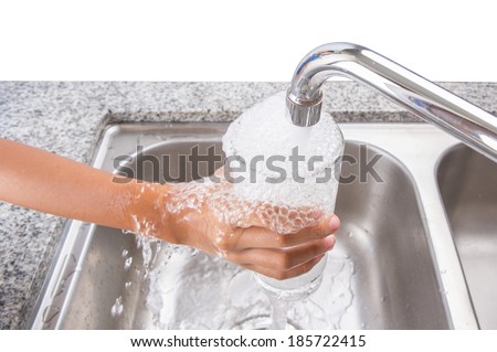 Young girl hand filling tap water into a drinking glass at the kitchen sink