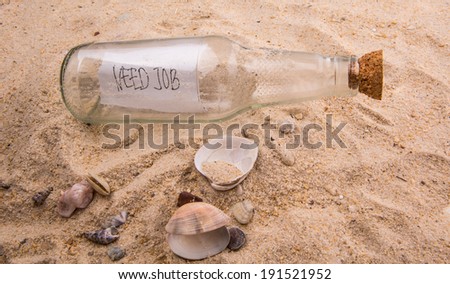Concept image of NEED JOB message written on a piece of paper in a glass bottle on beach sand