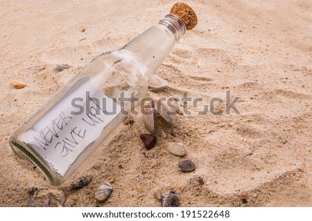 Concept image of NEVER GIVE UP message written on a piece of paper in a glass bottle on beach sand