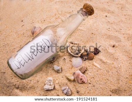 Concept image of DELIVERED message written on a piece of paper in a glass bottle on beach sand