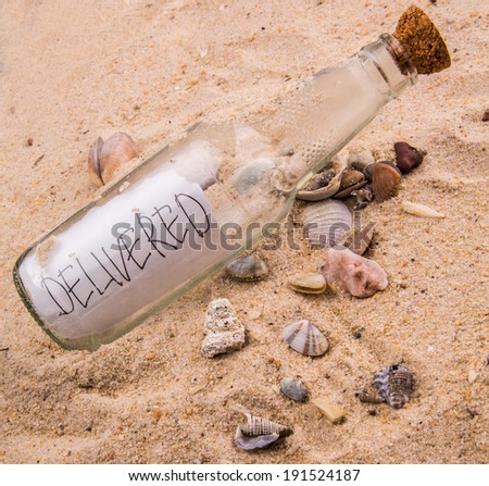 Concept image of DELIVERED message written on a piece of paper in a glass bottle on beach sand