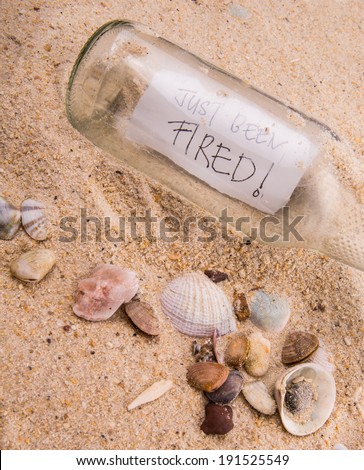 Concept image of word JUST BEEN FIRED message in a glass bottle on beach sand