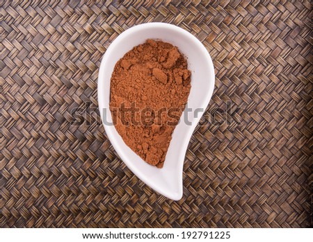 Cocoa powder for making drinks in a white ceramic container over wicker background