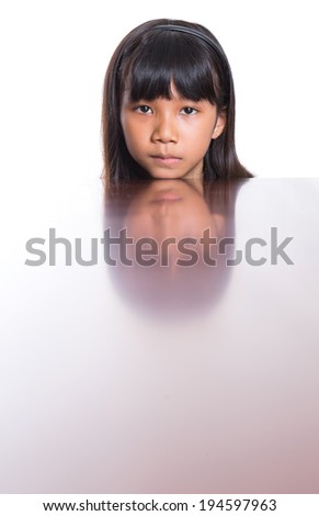 Young Asian Malay girl with her face reflection on a wooden table surface