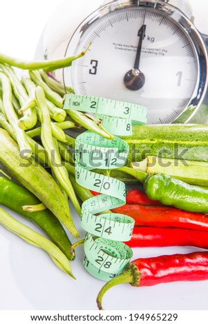 Weight scale, measuring tape and vegetables