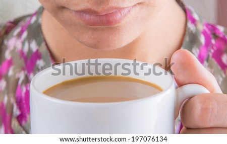 An adult woman sipping coffee with creamer