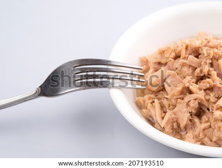 Flaked pieces of tuna in white bowl with a fork