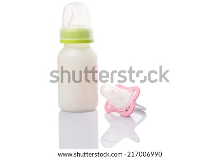 Baby pacifier and a bottle of baby formula milk over white background