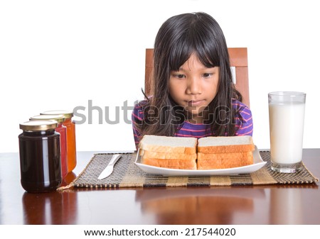 Young Malay Asian preteen girl having breakfast with bread and jam with a glass of milk