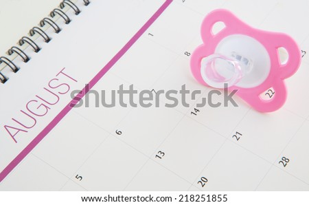 Concept image of baby girl pregnancy delivery due date with calendar page and pink  pacifier.