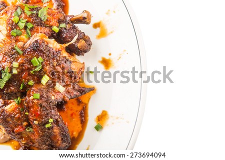 Roasted chicken piece coated with soy sauce and chili sauce on white plate
