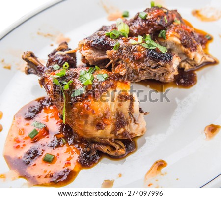 Malaysian dish of roasted chicken pieces coated with soy sauce and chili sauce on white plate