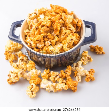 Caramel popcorn in blue pot over white background