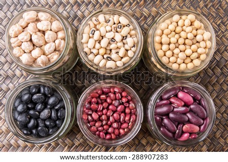 Black eye peas, chickpeas, adzuki beans, soy beans, black beans and red kidney beans in mason jars on wicker tray