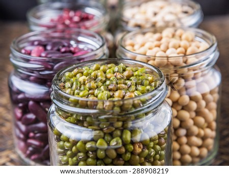 Black eye peas, chickpeas, adzuki beans, mung bean, soy beans, black beans and red kidney beans in mason jars on wicker tray