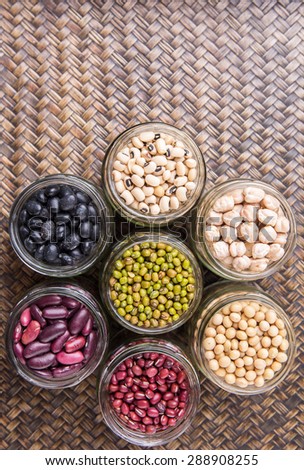 Black eye peas, chickpeas, adzuki beans, mung bean, soy beans, black beans and red kidney beans in mason jars on wicker tray