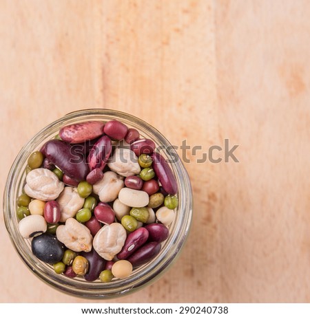 Mix bean of black eye peas, mung bean, adzuki beans, soy beans, black beans and red kidney beans in a mason jar over wooden background