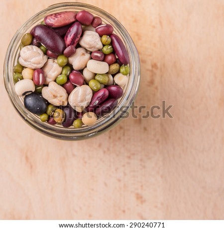 Mix bean of black eye peas, mung bean, adzuki beans, soy beans, black beans and red kidney beans in a mason jar over wooden background