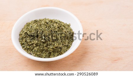 Dried parsley herb in white bowl over wooden background