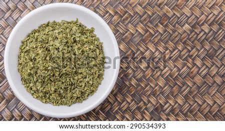 Dried parsley herb in white bowl over wicker background